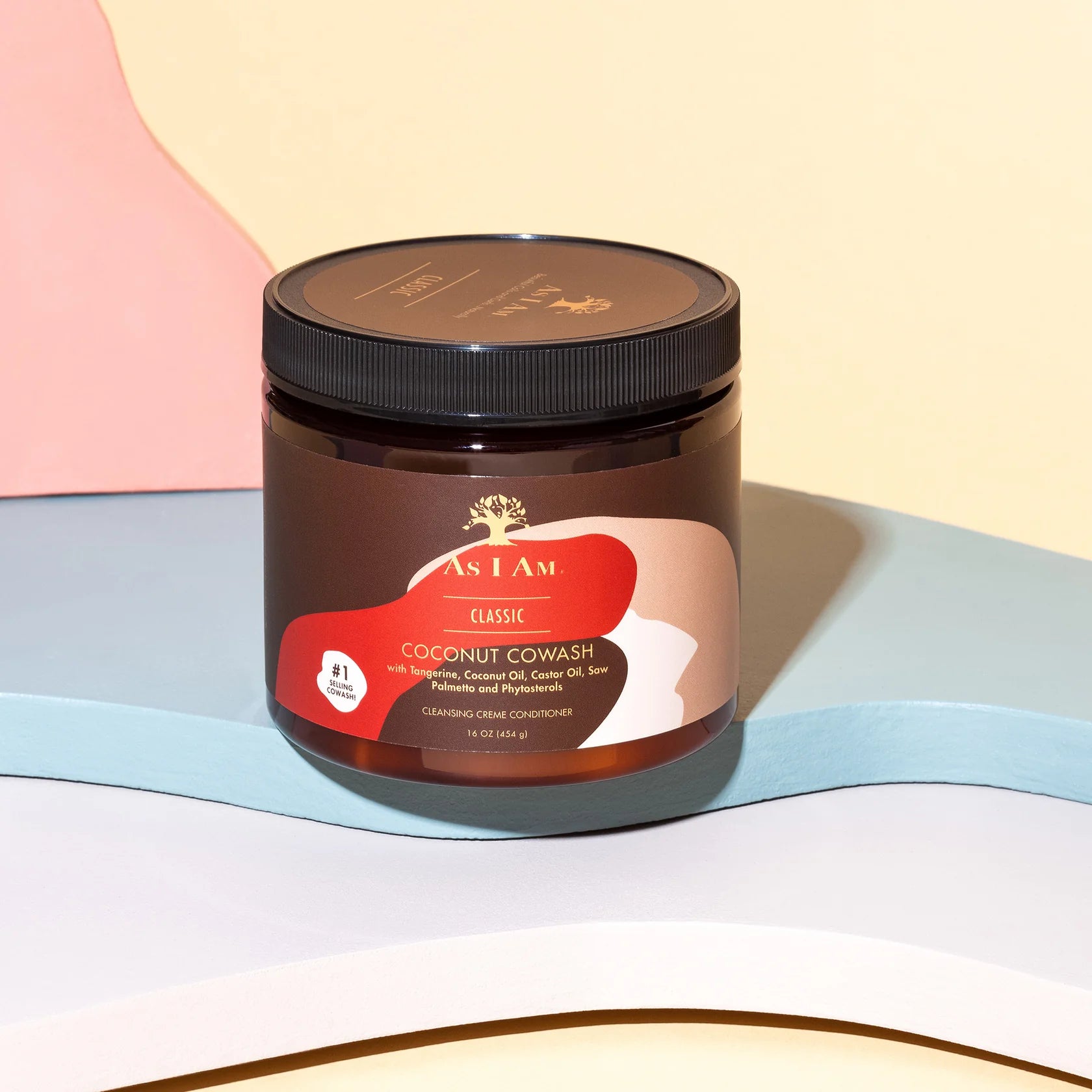 En brun dåse med en etiket indeholder As I Am Classic Coconut Co-Wash. Produktet er designet til at rense og fugte krøllet hår. Etiketten har et billede af en kokosnød og nævner ingredienser som kokosolien og castorolie.