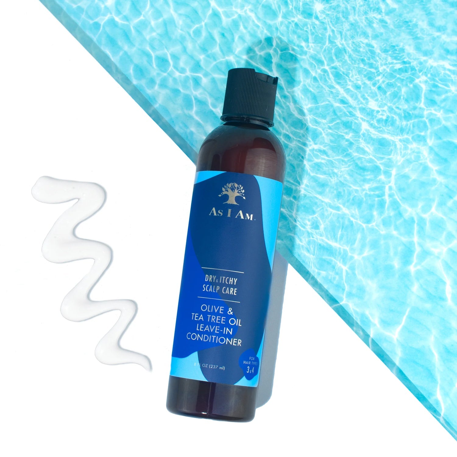En flaske As I Am Dry & Itchy Scalp Care Leave-in Conditioner står foran en baggrund, der minder om vand. En klat af den hvide conditioner er placeret ved siden af flasken.