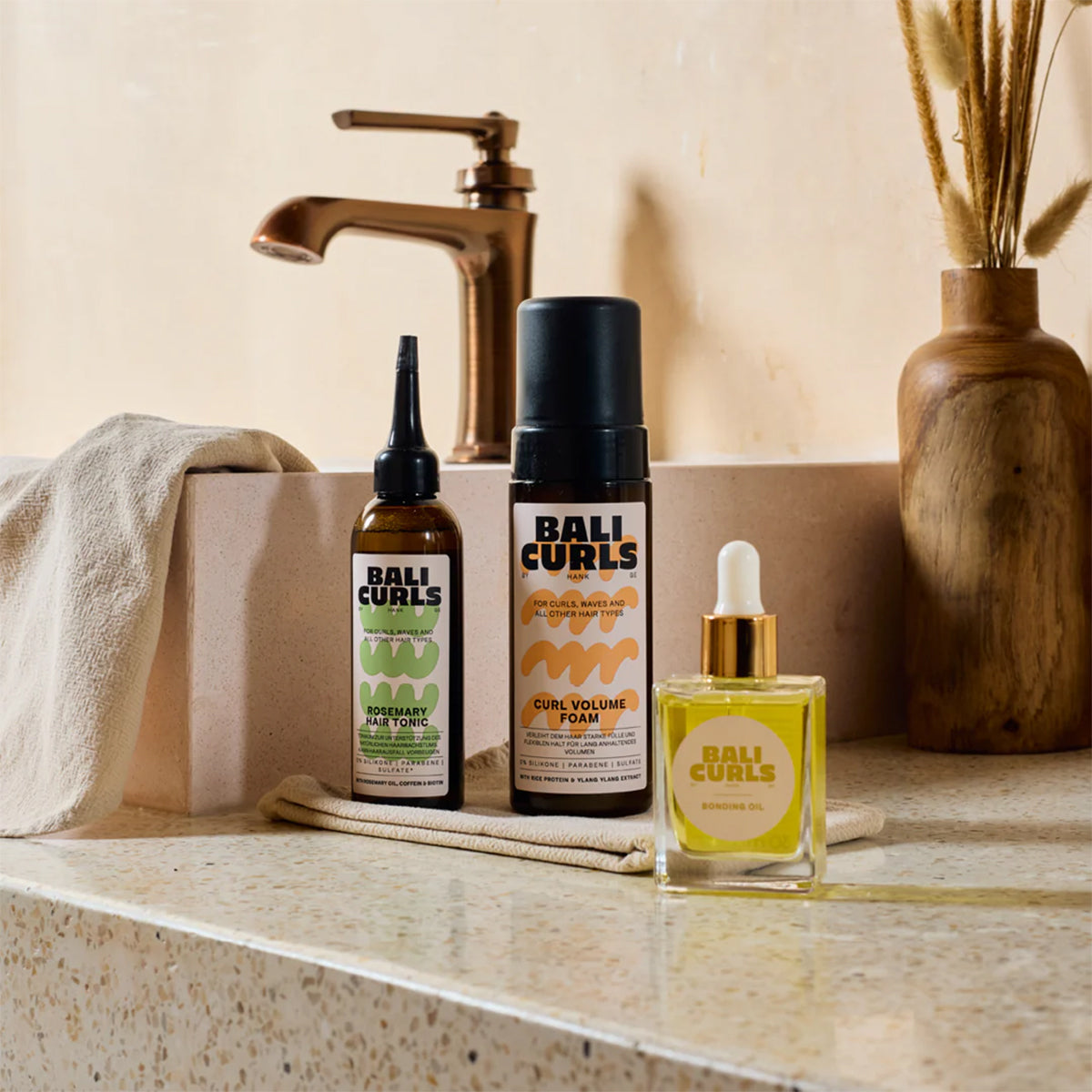 BALI CURLS produkter på badeværelsesbord – Rosemary Hair Tonic, Curl Volume Foam** og Bonding O i naturligt lys.
