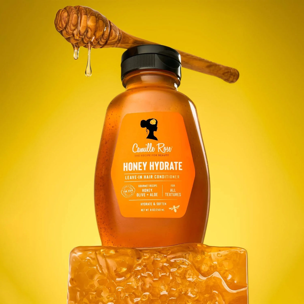 Camille Rose Honey Hydrate leave-in hårbalsam i flaske med honningdrypper og honningkage på gul baggrund.