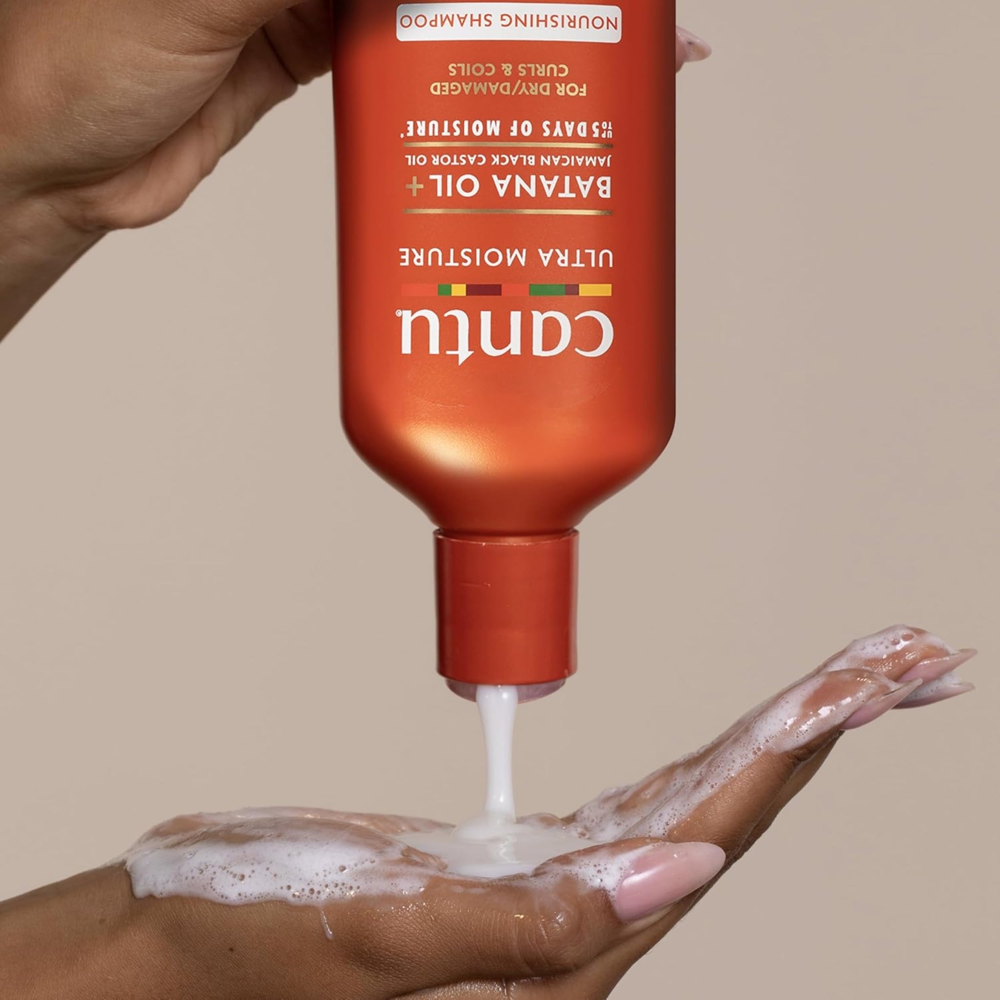 Cantu Ultra Moisture Nourishing Shampoo med Batana Oil hældes skummende i hånden.