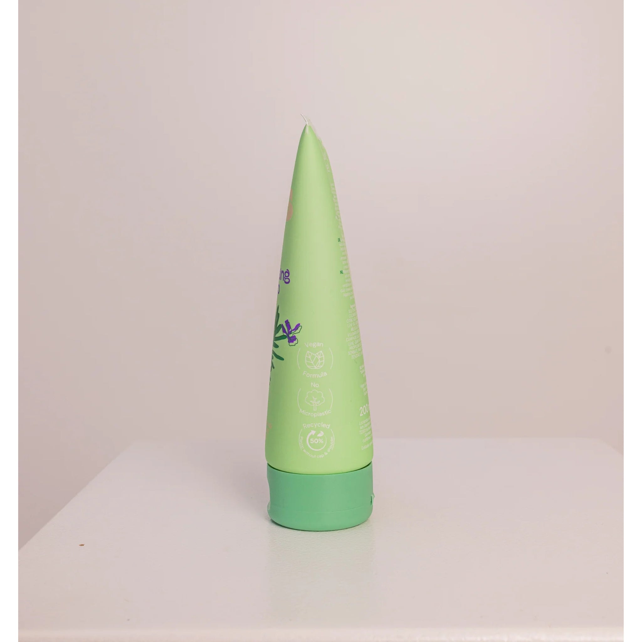 Grøn tube shampoo med grønt låg, veganskt og genbrugt plastik, står oprejst på hvid bordplade.