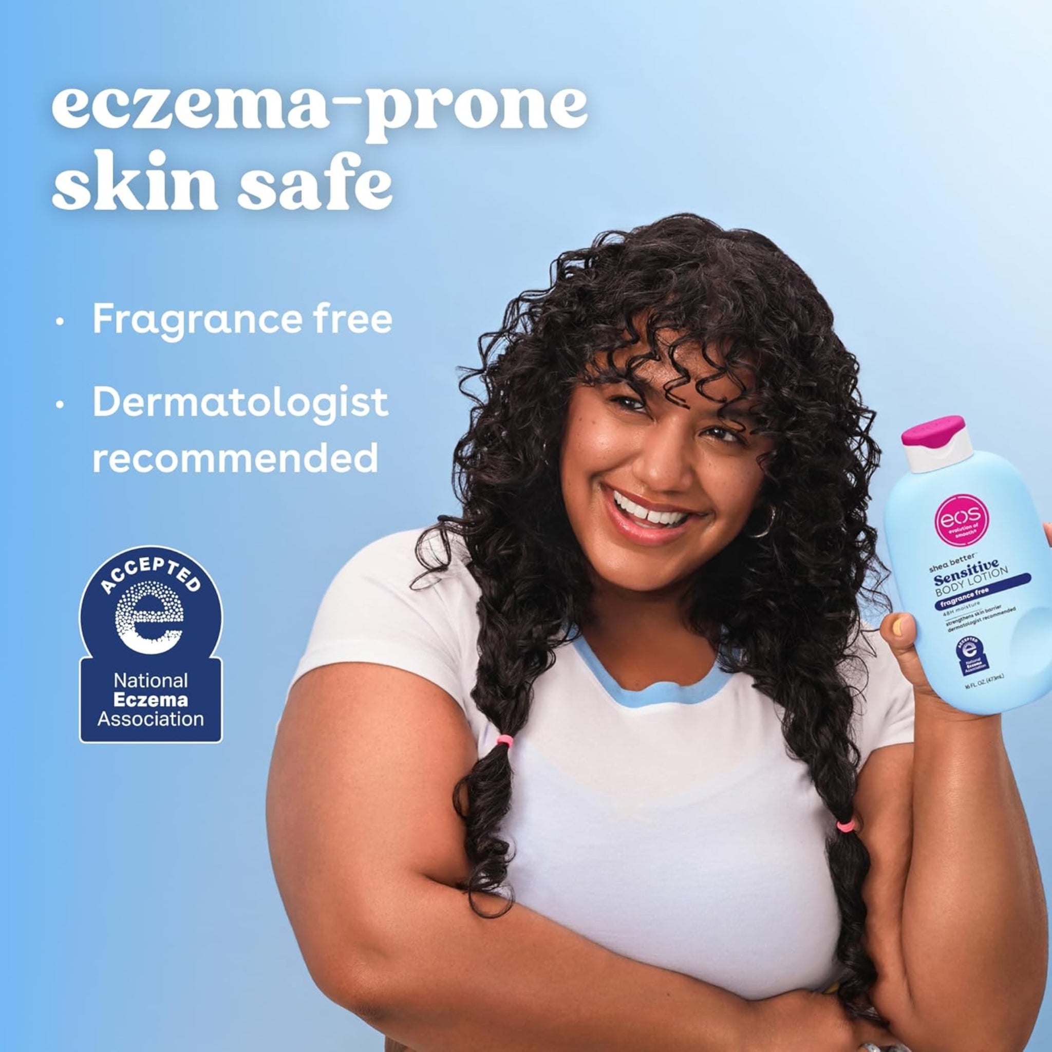 Kvinde med krøllet hår smiler og holder eos Shea Better Sensitive Body Lotion, eczema-prone skin safe, fragrance free.