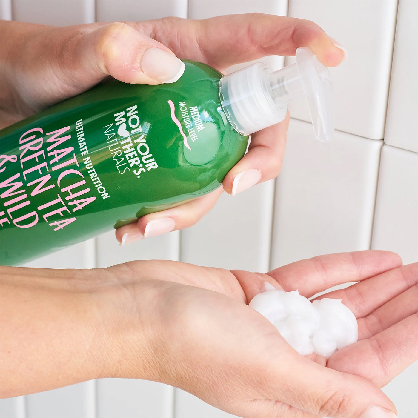 Not Your Mother's Matcha Green Tea & Wild Apple Blossom Conditioner 473 ml pumpes i hånden foran hvide fliser.
