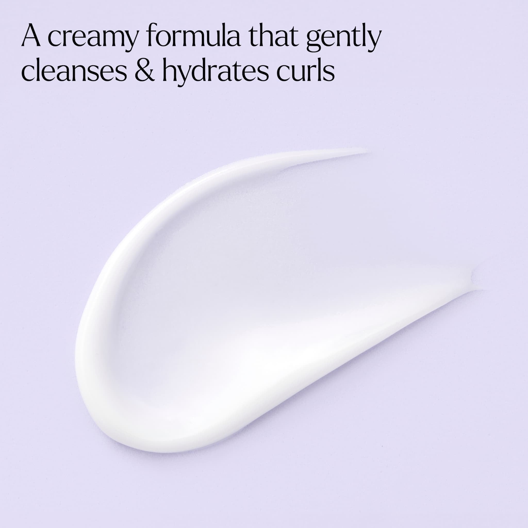 Cremet hvid shampoo-tekstur der renser og hydrerer krøller, mod lyslilla baggrund.