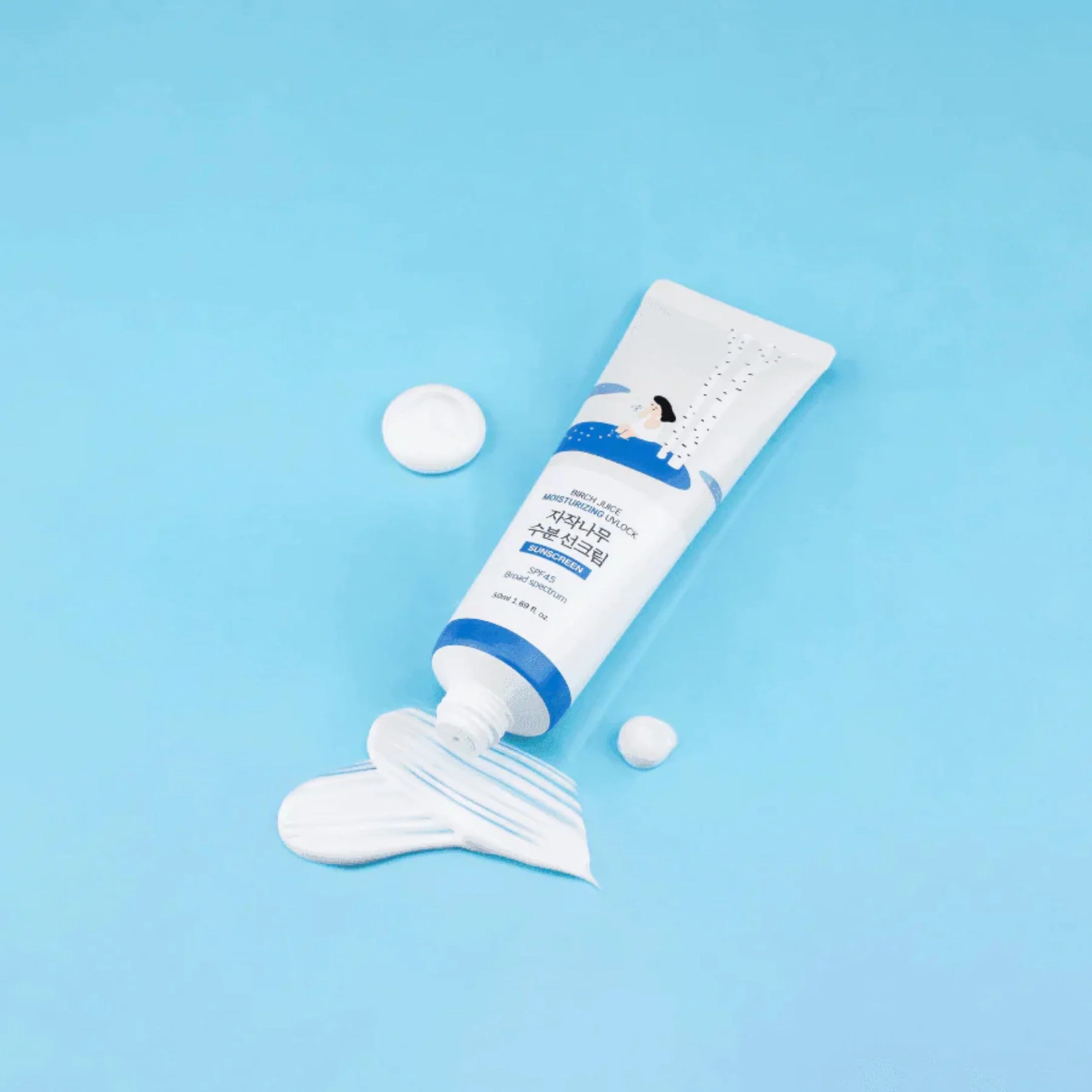 Round Lab Birch Juice Sun Cream 50ml tube på blå baggrund med hvid solcreme smurt ud foran.